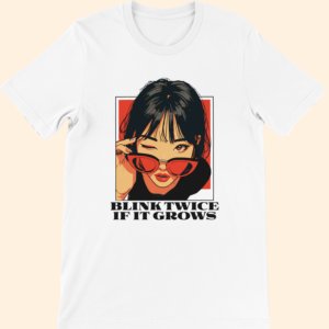 White T-shirt featuring illustrated woman wearing red sunglasses with “Blink Twice If It Grows” text