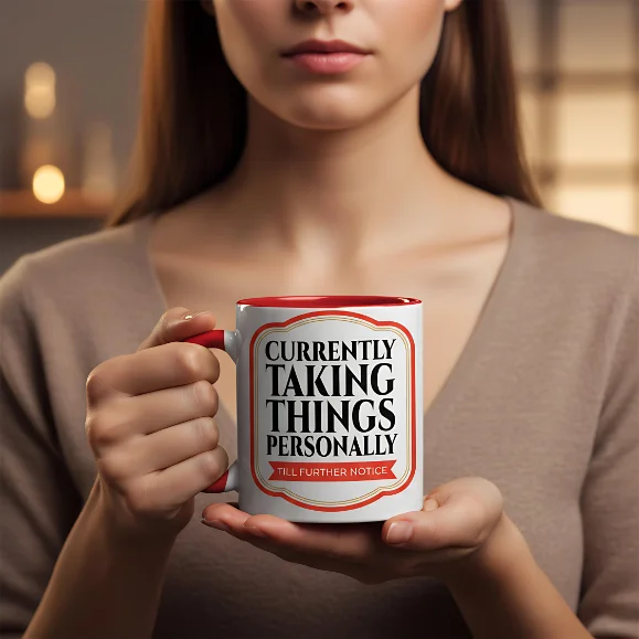 Currently Taking Things Personally Red Handle Mug Held Person holding a white Currently Taking Things Personally mug with a red handle indoors.