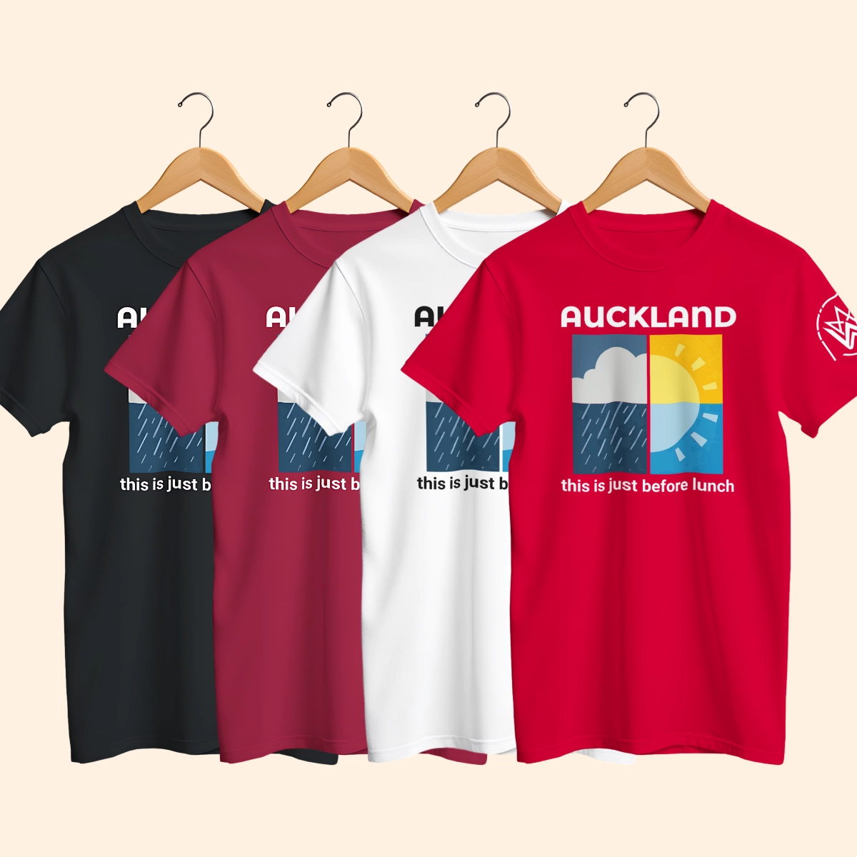 Four Auckland Weather T-shirts in black, cardinal red, white and red shown on wooden hangers