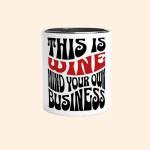 White ceramic mug with black interior featuring Mind Your Own Business text design on the front.