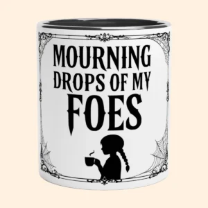 White ceramic mug with black interior featuring Mourning Drops of My Foes text, decorative border and a small figure holding a cup.