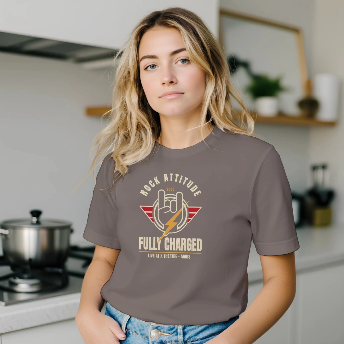 Woman wearing a pebble colour Rock Attitude Fully Charged T-shirt in an indoor kitchen setting.