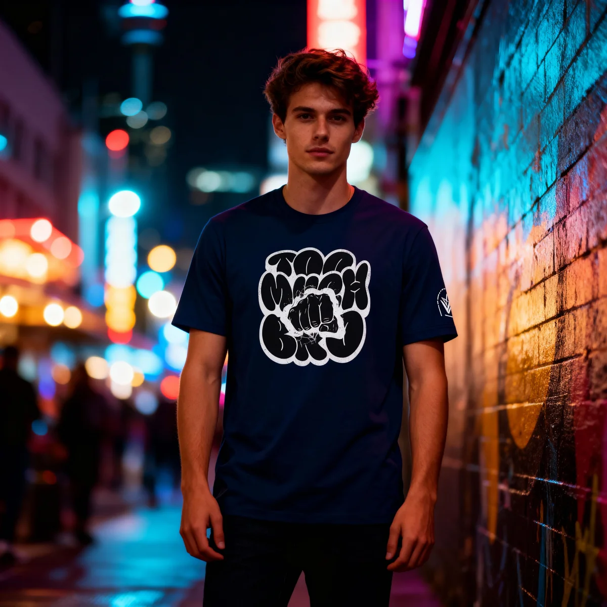 Model wearing a navy Too Much Bro T-shirt with front artwork in a night street setting.